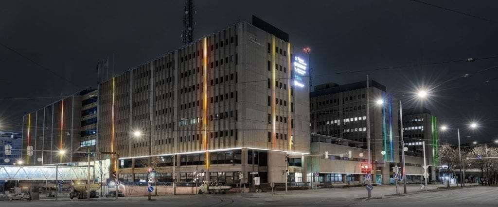 Havainnekuva, jossa Värivuoto-valotaideteos näkyy rakennusten seinissä yöllä Helsingin Pasilassa.