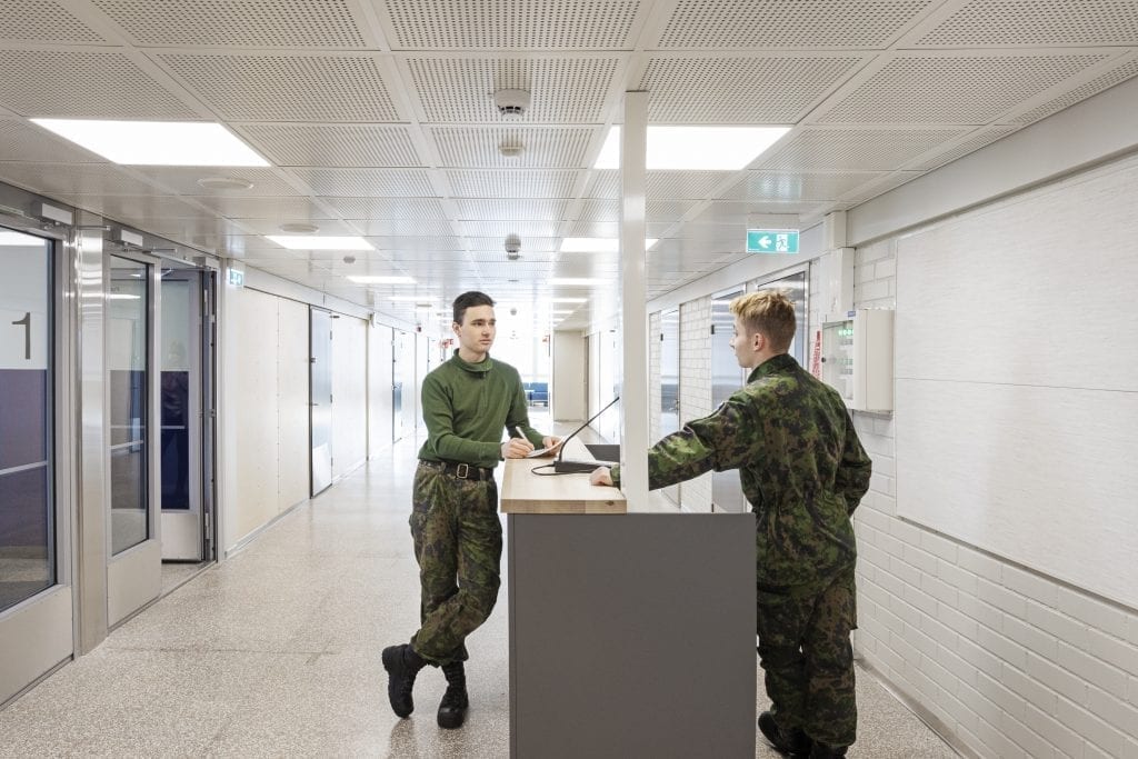 Kaksi henkilöä armeijan vaatteissa keskustelee käytävällä.